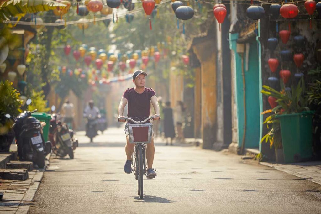 Traveler cycling through lantern-decorated streets – the most relaxing and sustainable way to get around Hoi An.