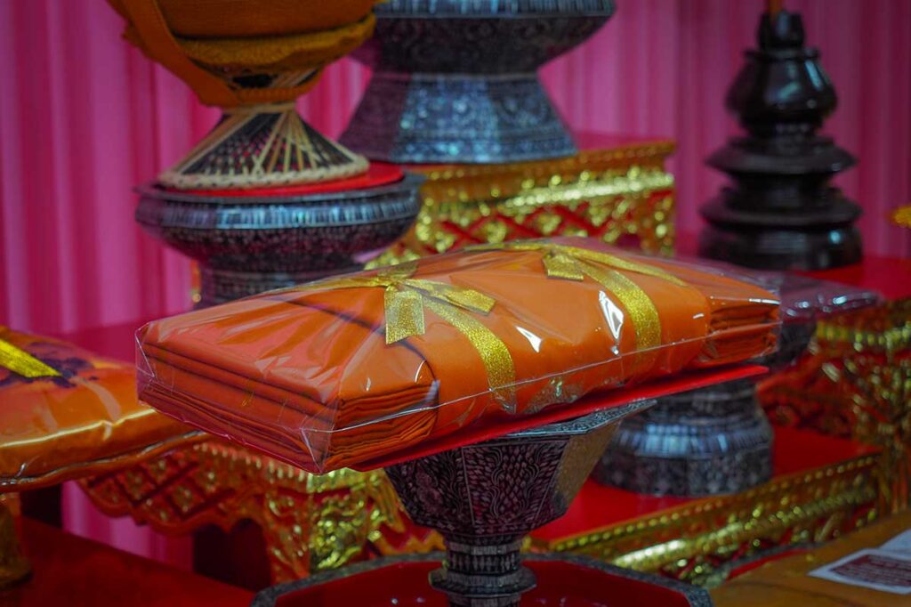 Golden bowls with saffron monk robes for offering at the Kathina Ceremony.