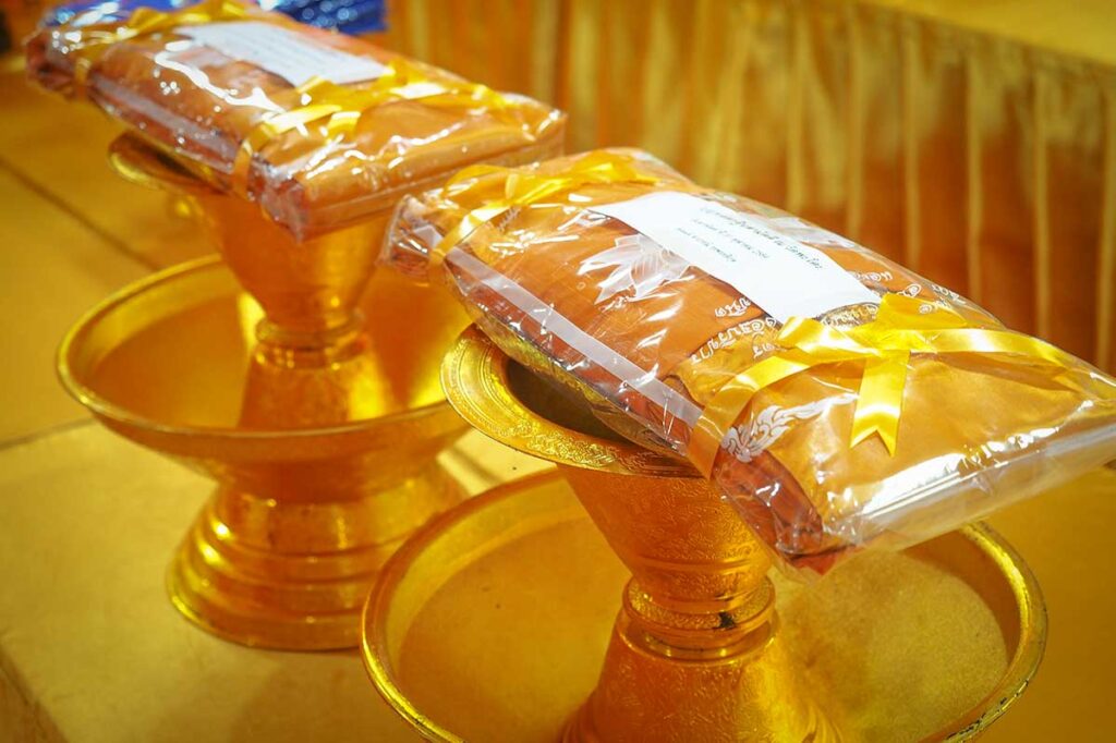 New saffron monk robes wrapped with golden ribbons for offering at a Kathina Ceremony