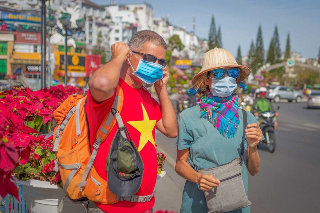 tourists in Vietnam wearing face masks while walking in a busy city street