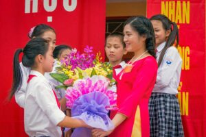 Vietnamese students presenting flowers to their teacher during a Vietnamese Teachers’ Day celebration at school.