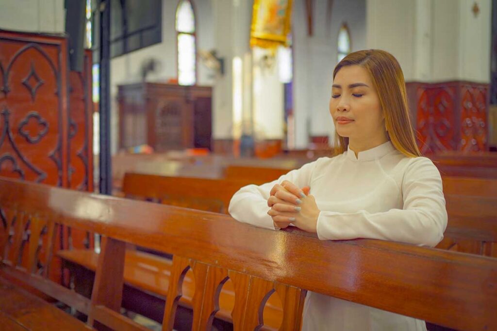 Vietnamese woman praying during Easter mass inside a Catholic church in Vietnam.