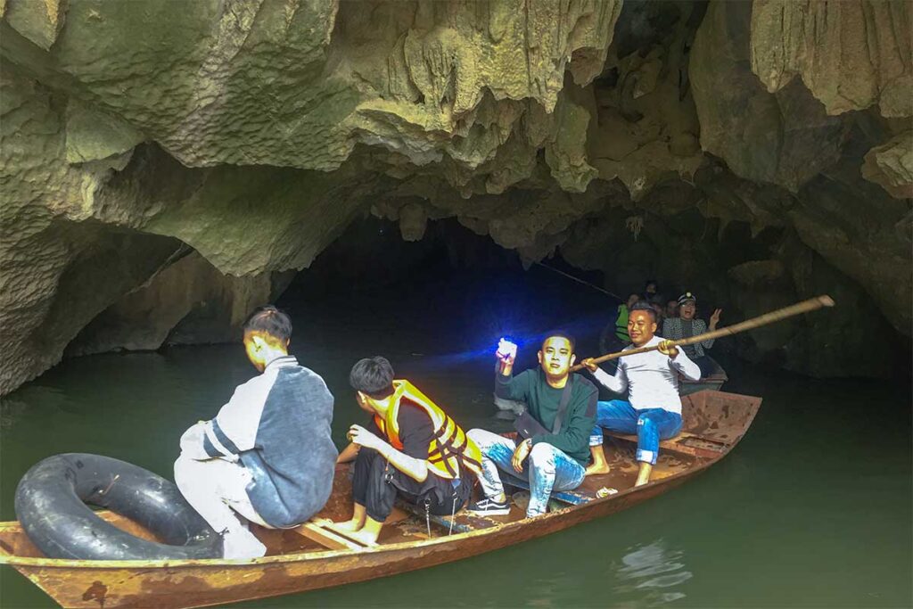 A small rowing boat comes out of a cave with domestic tourists at Ao Dong Tourist Area