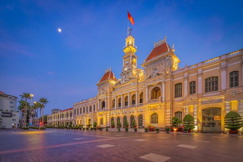 Ho Chi Minh City Hall illuminated at night, showcasing French colonial architecture with soft lighting and open square in front