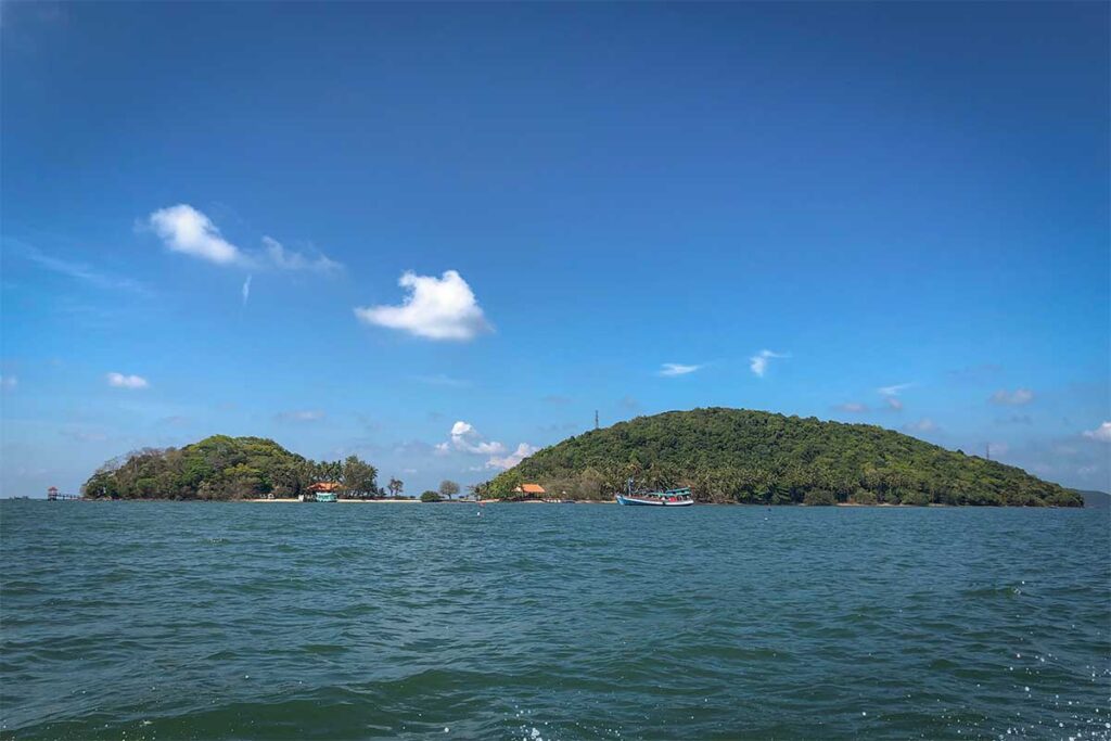 Ba Lua Islands viewed from the sea on a sunny day, with green hills, fishing boats, and clear blue skies in Kien Giang Province, Vietnam.