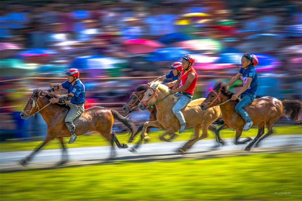 Four horses with riders are racing at Bac Ha Horse Racing Festival