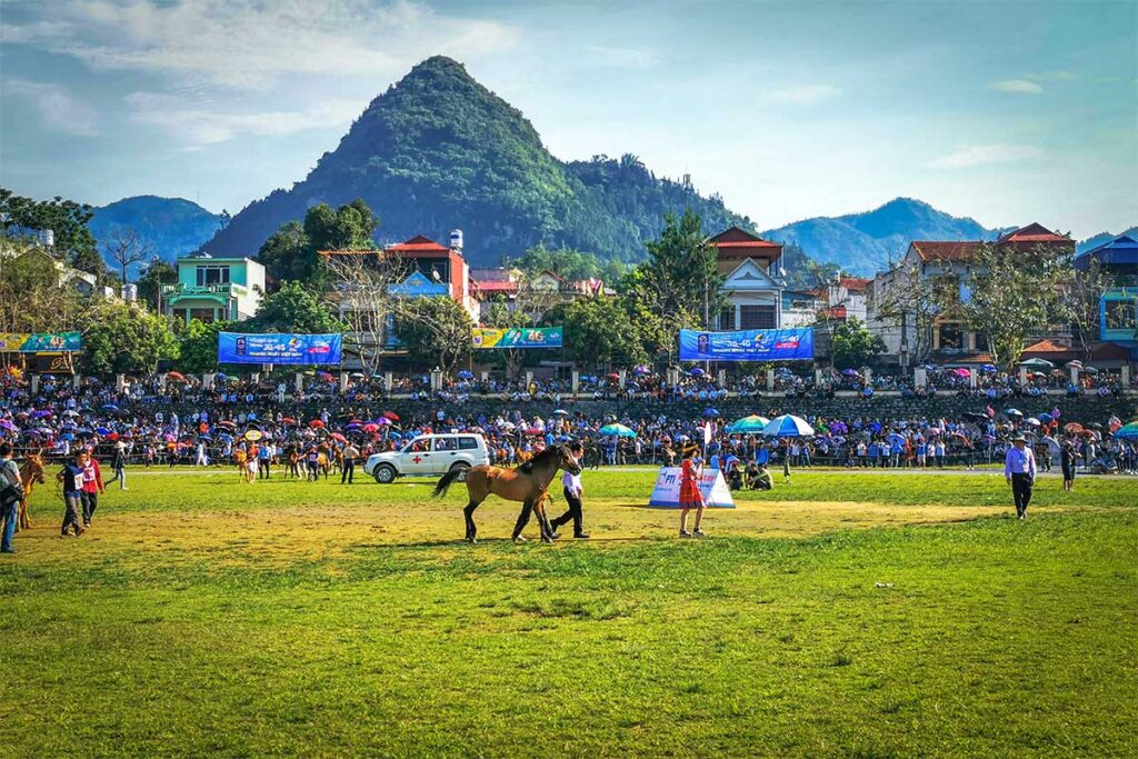 Horse racing and stands full of people inside the Bac Ha Arena during Horse Racing Festival