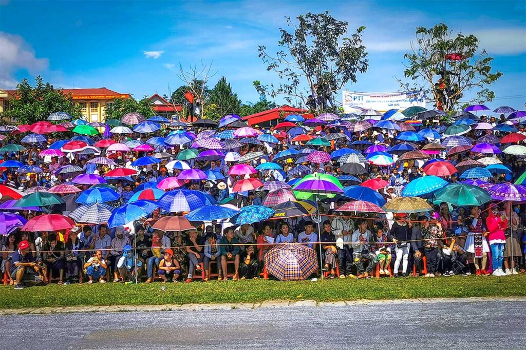 Stands of Bac Ha Stadium full of people holding umbrellas against the sun during Bac Ha Horse Racing Festival