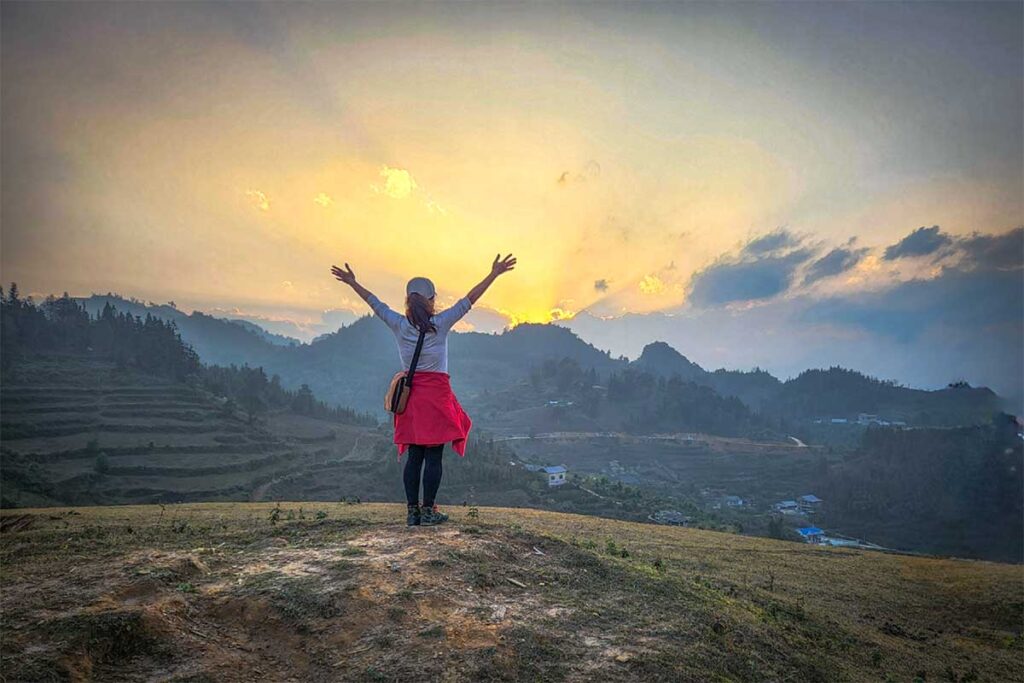 A girl doing a trekking in Bac Ha with sunset on the background of the mountains and terraced rice fields
