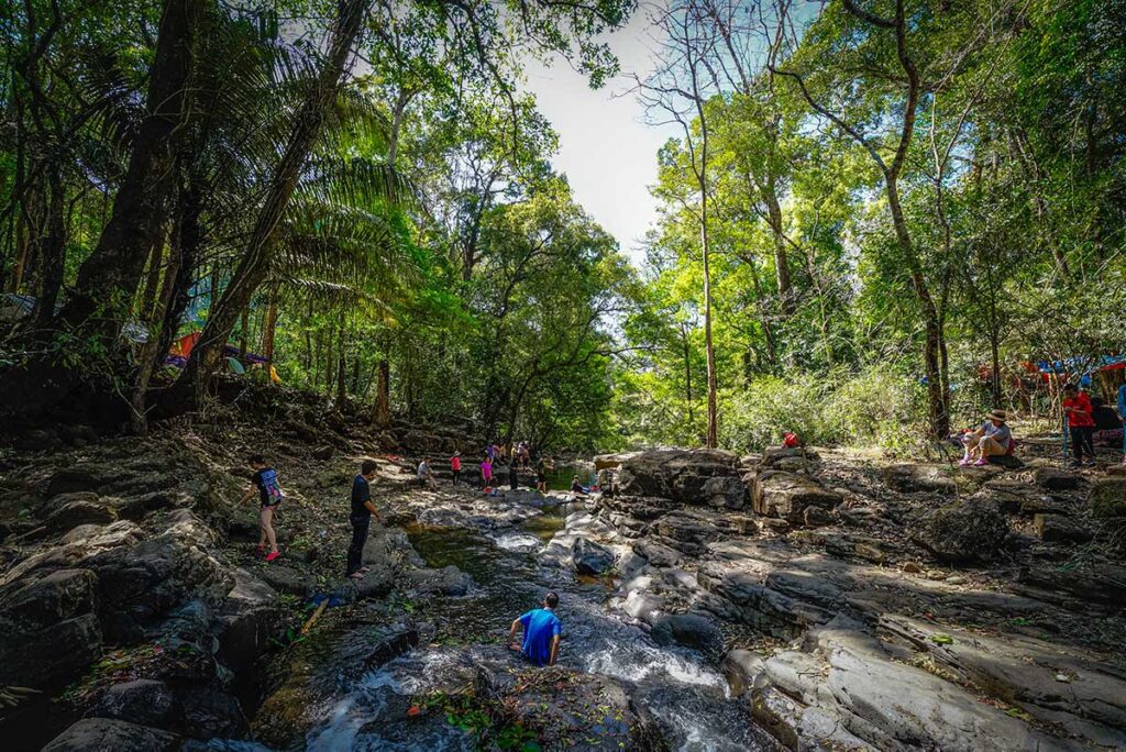 Tourists part of a trekking group inside Bu Gia Map National Park are resting at a stream