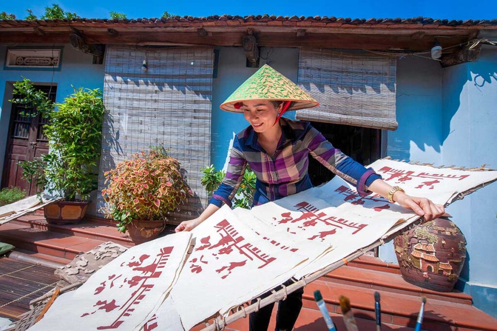 woman drying paintings outside in Dong Ho Village