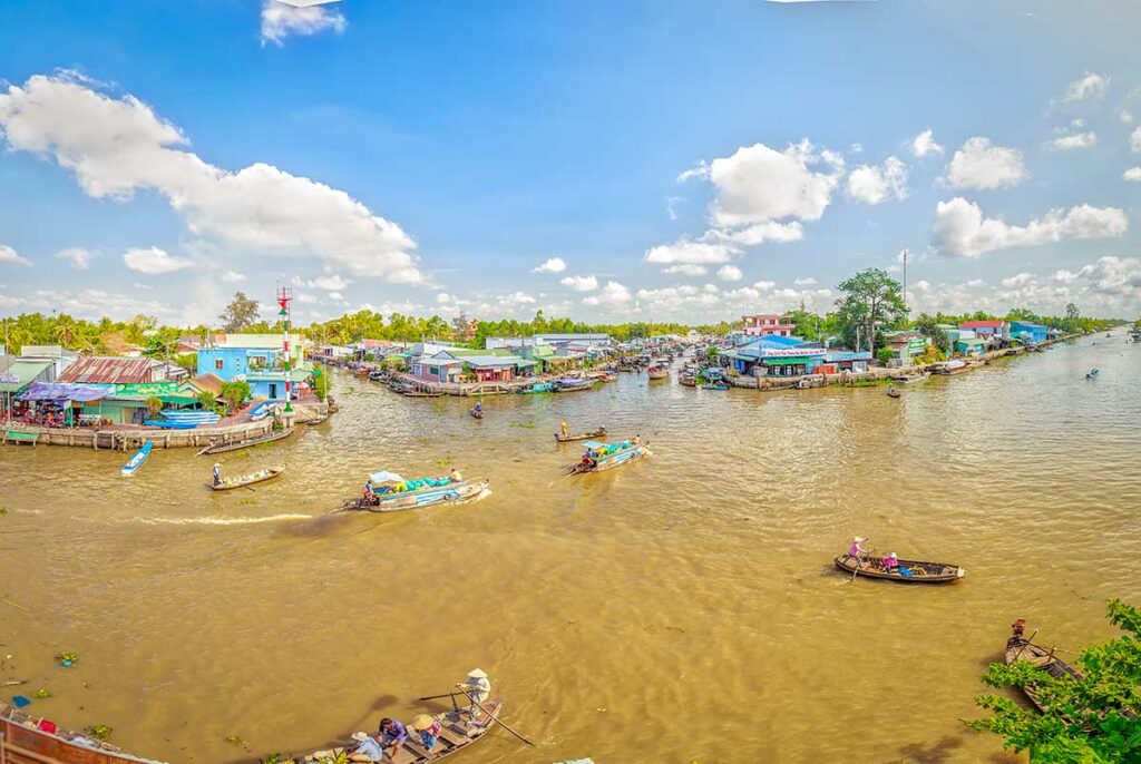Canals of Hau Giang Province, Vietnam – traditional wooden boats navigating a bustling Mekong Delta waterway lined with houses and shops.