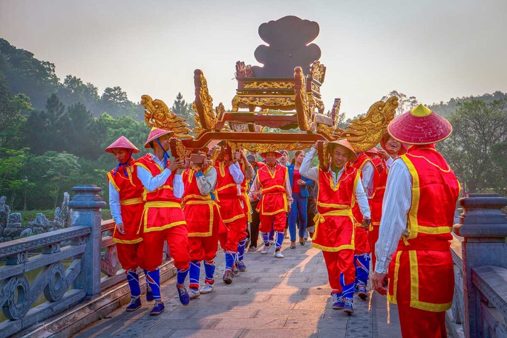 People in colorful traditional temple clothes carrying a golden chair in a parade during Hung Kings Temple Festival
