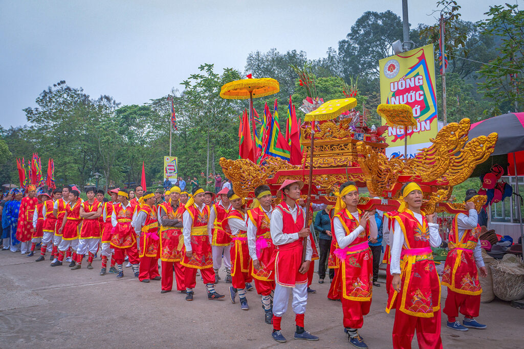People in colorful traditional temple clothes carrying a golden object  in a parade during Hung Kings Temple Festival