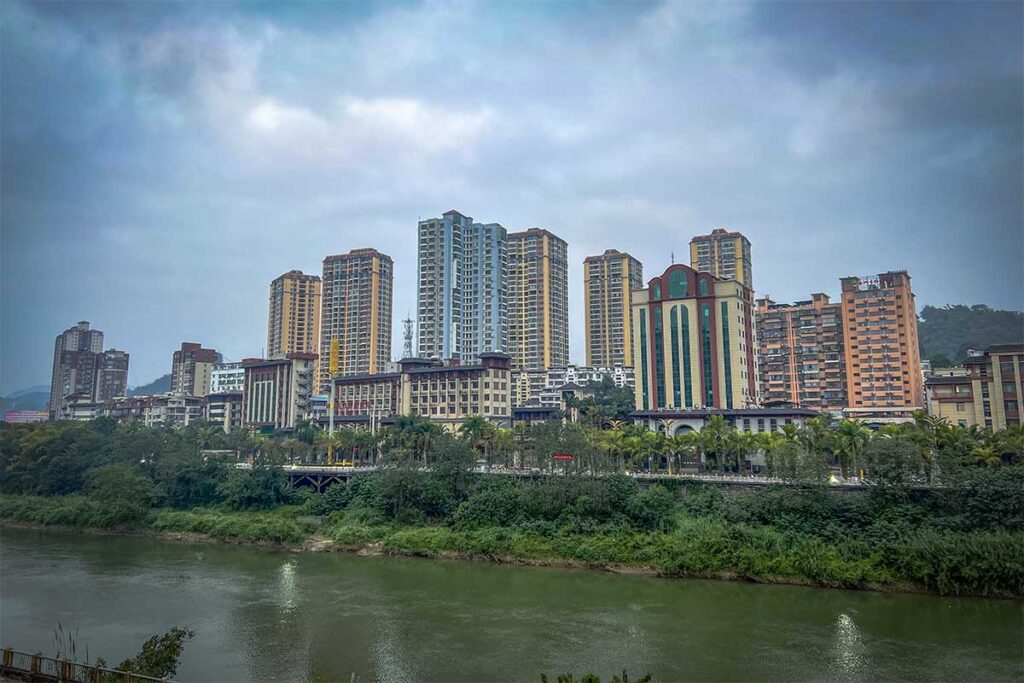A river with on the other side larger apartment buildings located in china viewed from the town of Lao Cai in Vietnam