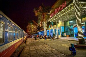 Lao Cai Railway Station at night with train of Reunification Express parked on the station at big letters of Ga Lao Cai on the station building