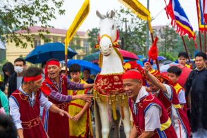 Colourful dressed locals carrying a statue of a horse through the streets during Lim Festival in Bac Ninh