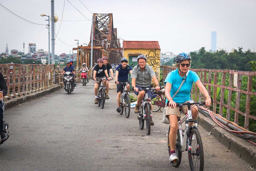 Cycling tour group riding across Long Bien Bridge during a Hanoi bike tour
