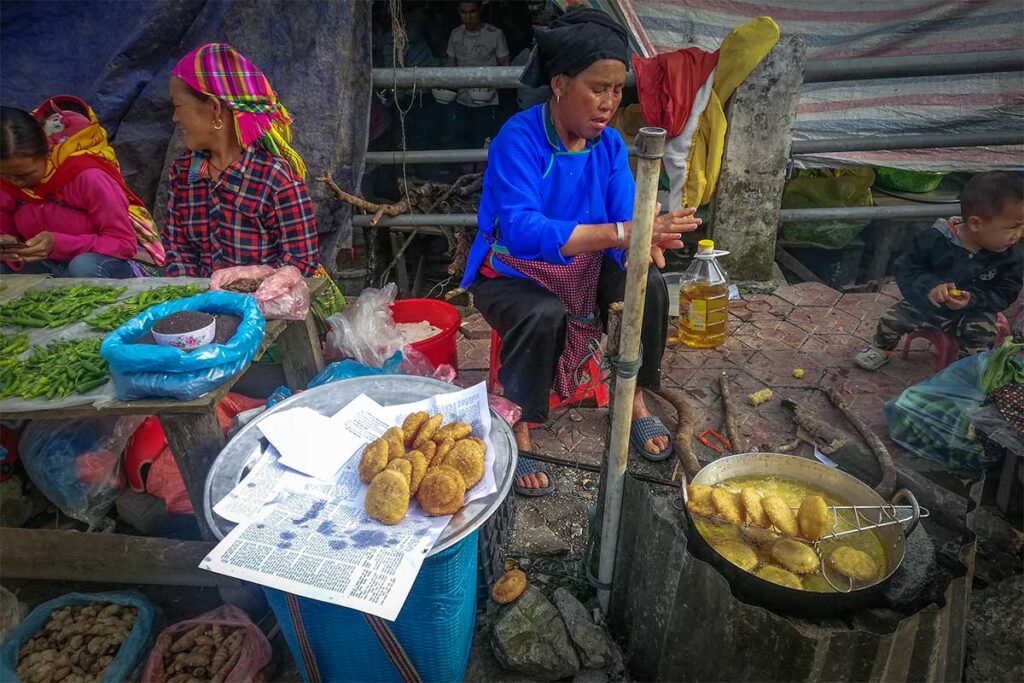Ethnic woman selling frying local snacks to sell on Lung Phin Market