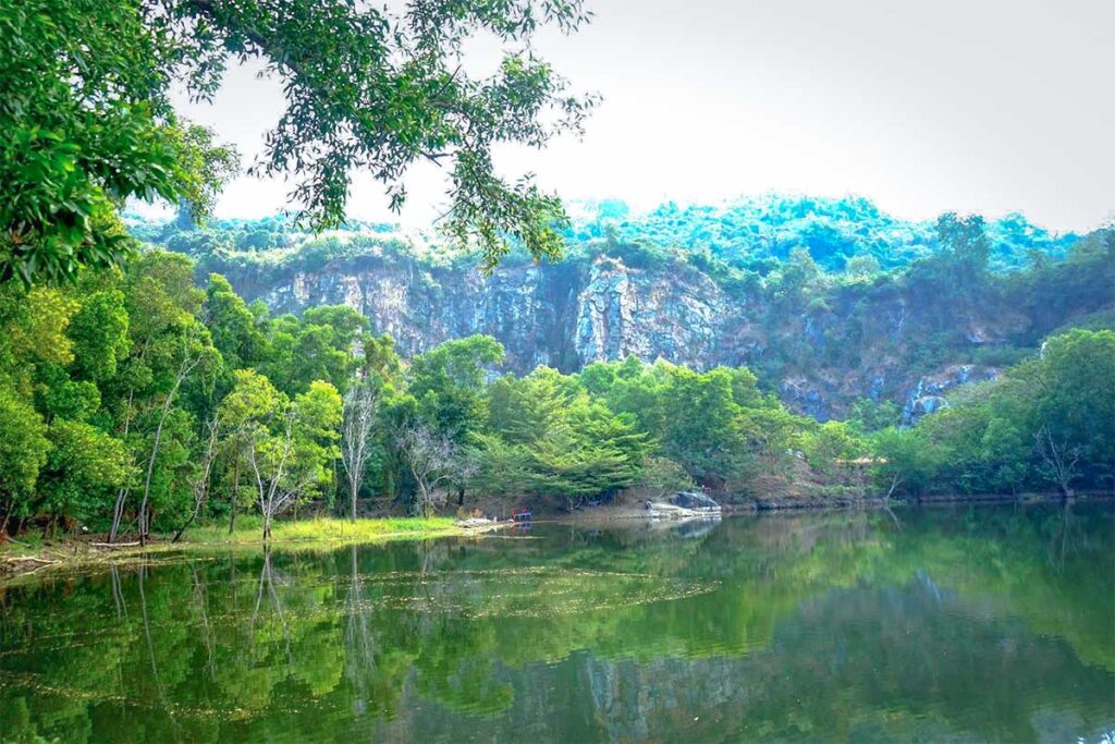 A lake with cliffs and trees alongside it part of Ma Thien Lanh Valley in Tay Ninh