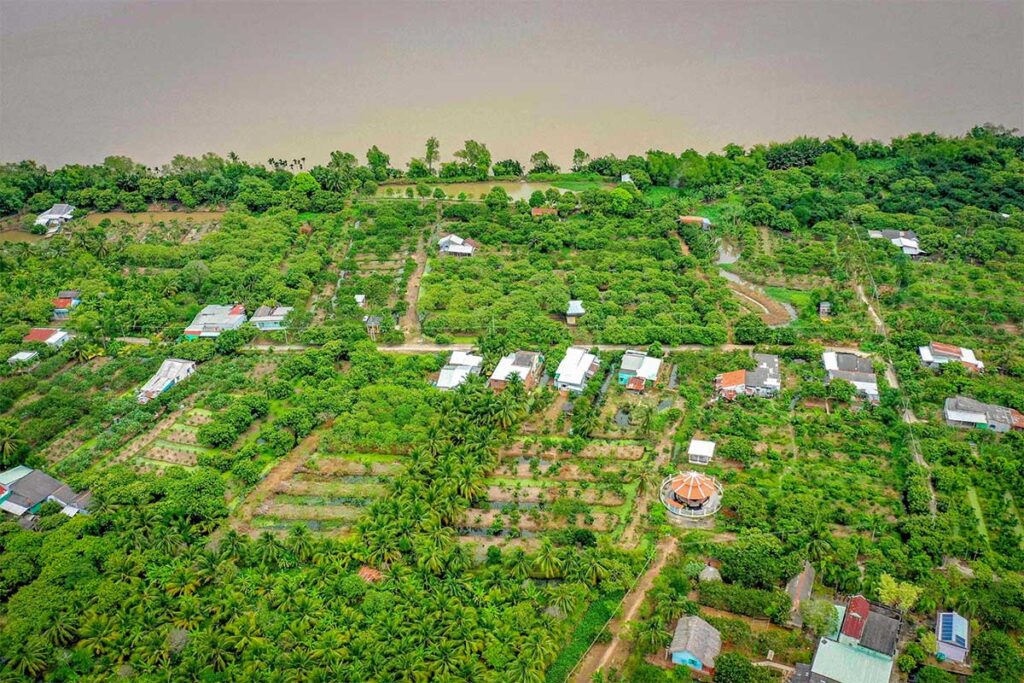 Aerial view of My Phuoc Island in Soc Trang showing lush fruit orchards, rural houses, and the river shoreline.