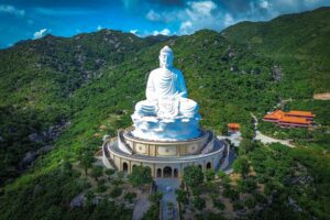 Massive seated Buddha statue of Ong Nui Temple surrounded by green mountains near Quy Nhon.