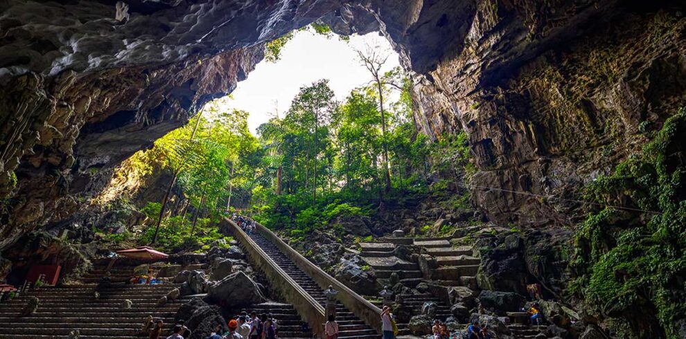 Massive entrance of Huong Tich Cave with steps leading down into the sacred site