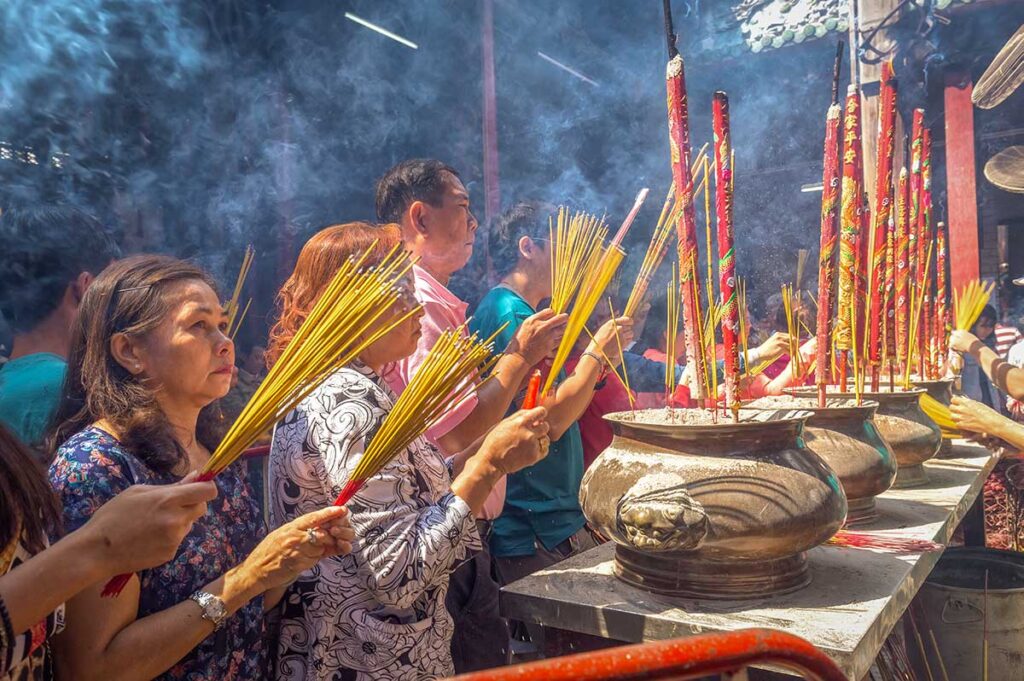 Local people burning incense and praying inside a Chinese temple in Chinatown Ho Chi Minh City Saigon