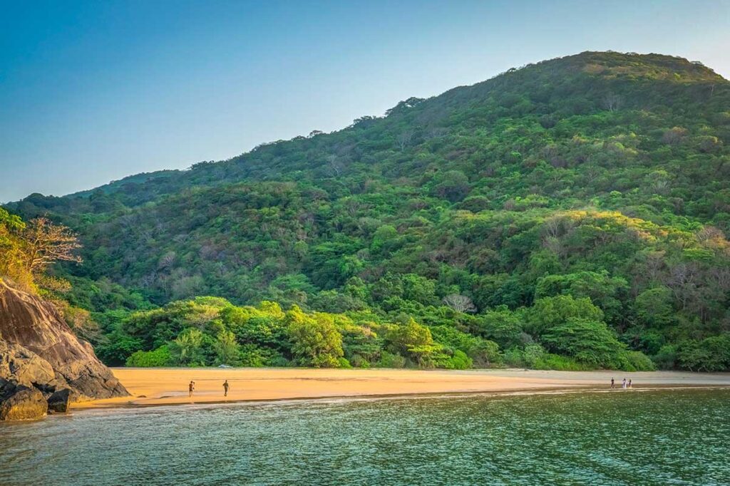 Suoi Nong Beach in Con Dao, a pristine sandy beach with few visitors, surrounded by mountains and dense forest.