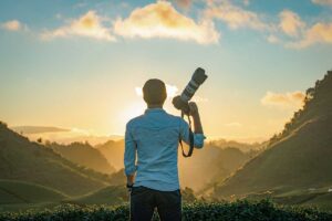 Photographer standing on rolling tea hills in Moc Chau at sunrise, overlooking green plantations and mountain scenery
