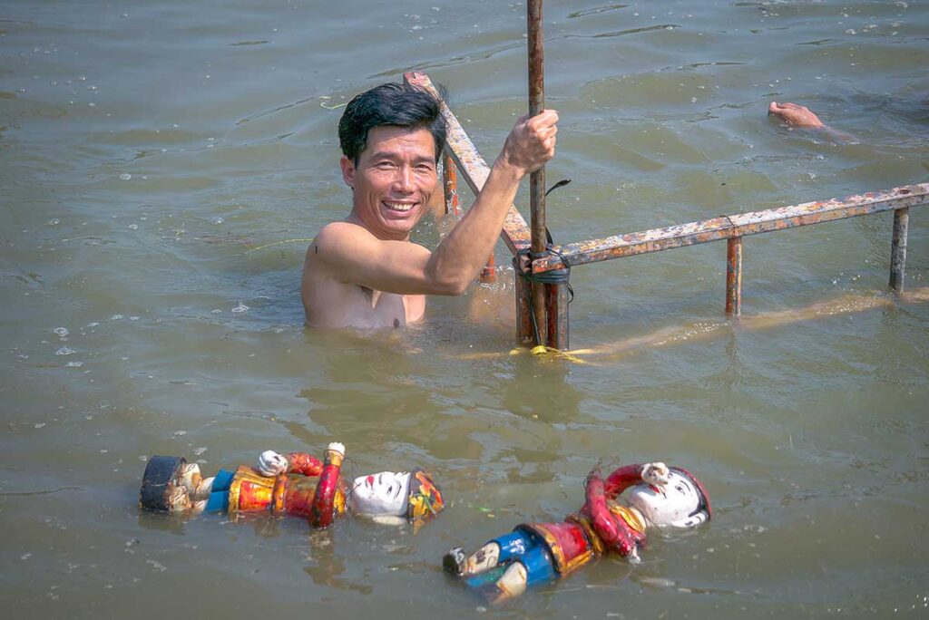 A man sitting in the water setting up a stage for a water puppet show in Thanh Hai Village in Hanoi