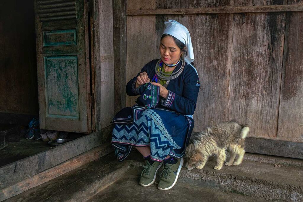 A White Dao girl sitting in the door opening of a traditional wooden ethnic house in Tuyen Quang