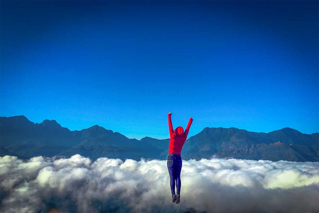 A girl jumping up so it looks she floats above the clouds in Y Ty