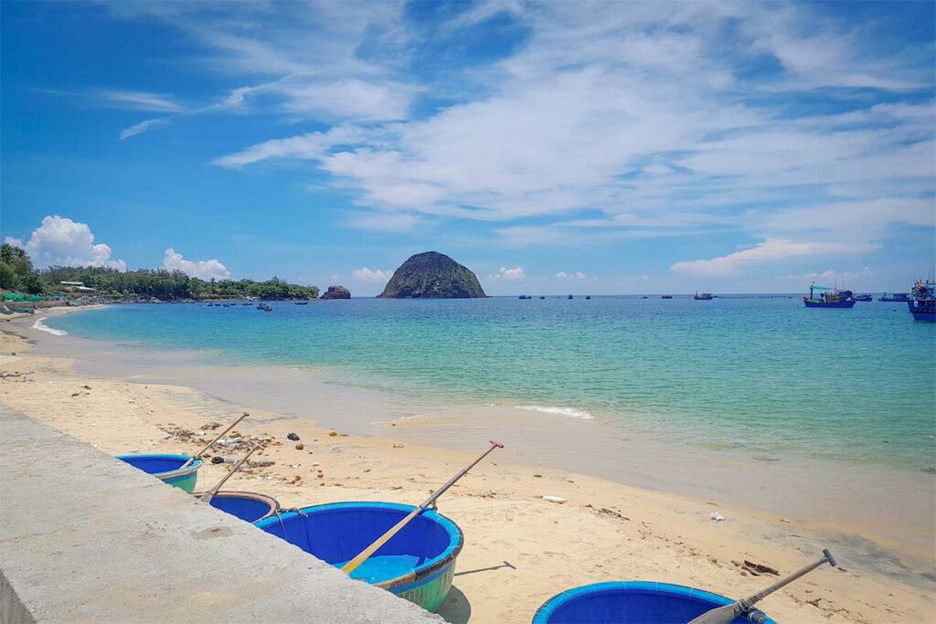 Yen Beach in Phu Yen with turquoise waters, fishing coracles on the sand, and Yen Island rising offshore.