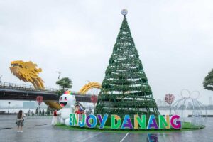 Da Nang in December – A festive scene with a large Christmas tree and decorations, with the iconic Dragon Bridge in the background.