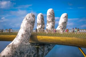 Da Nang in September – Tourists walking across the Golden Hand Bridge in Ba Na Hills, with good weather and a clear mountain view.