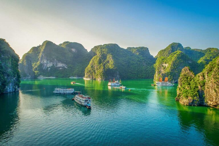 Cruise boats sailing through limestone islands in Halong Bay, one of the most famous places to visit in Vietnam