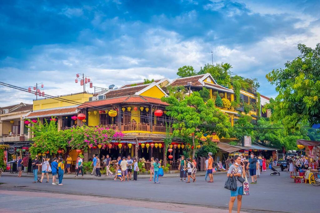 Lively streets of Hoi An Ancient Town in August with colorful lanterns and light clouds above, marking the transition from the dry summer to the wetter autumn months.