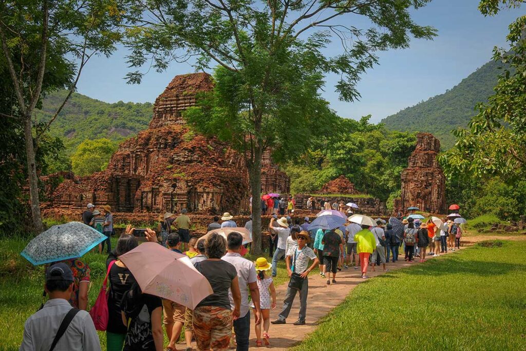 Visitors exploring the ancient My Son Sanctuary near Hoi An under the strong June sun, highlighting the hot and humid conditions of central Vietnam’s summer months.