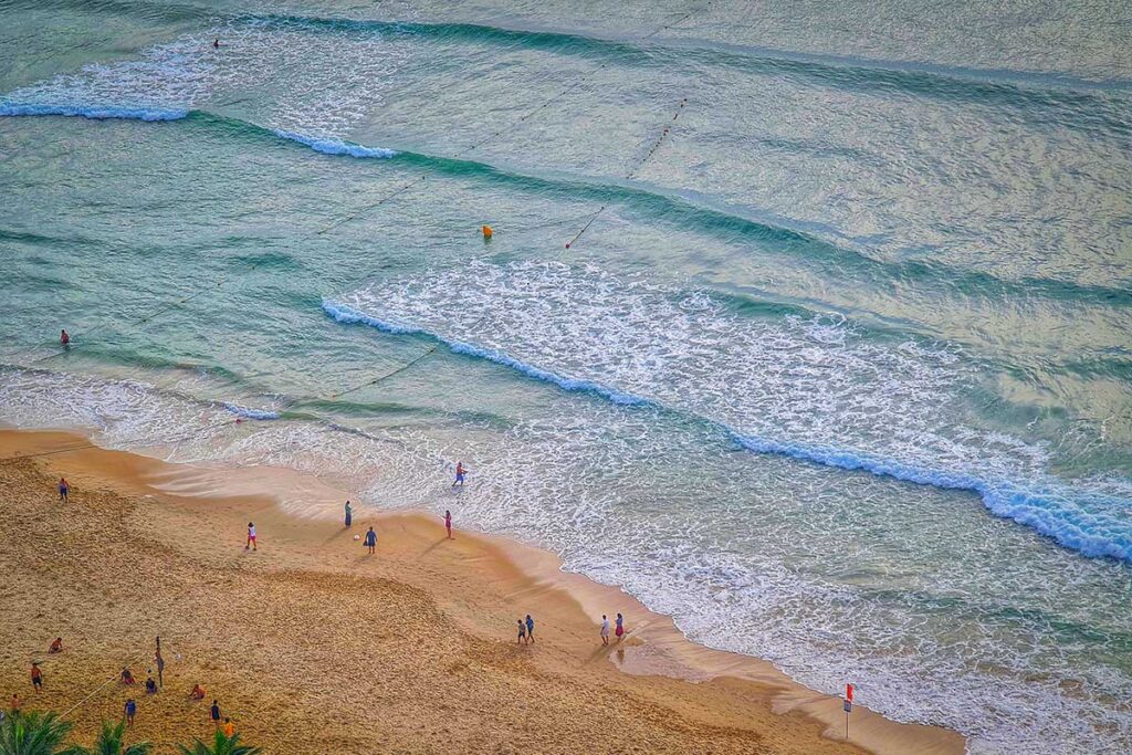 People swimming and walking along Hoi An’s beaches in June, when the sea is warm and the heat encourages cooling off in the water during the peak of summer.