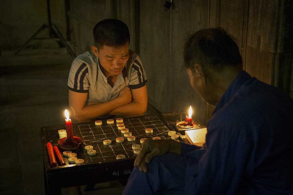 Locals playing traditional Chinese chess by candlelight during the Hoi An Lantern Festival, capturing the town’s nostalgic charm.