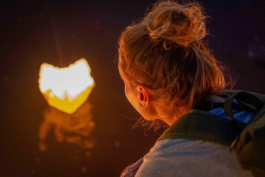 Woman releasing a paper lantern into the river during the Hoi An Lantern Festival, symbolizing good luck and peace.