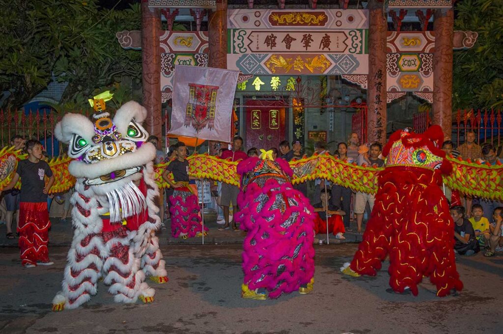 Lion dancers performing in front of a temple in Hoi An during the Mid-Autumn Festival, a colorful celebration with music and lanterns.