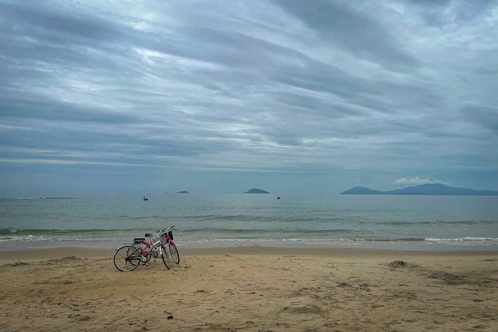 Bicycles parked on An Bang Beach in Hoi An in November, with calm seas and moody skies reflecting the peak of the rainy season along Vietnam’s central coast.