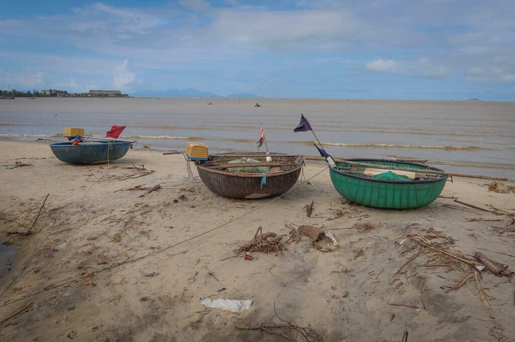 Round fishing boats on the beach near Hoi An in October, as the sea turns brownish and rougher due to seasonal rain and river outflow.