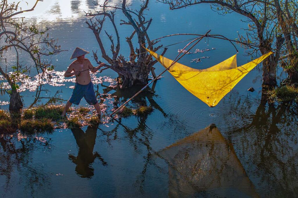 Hue in October - A man is fishing in a lagoon with nets