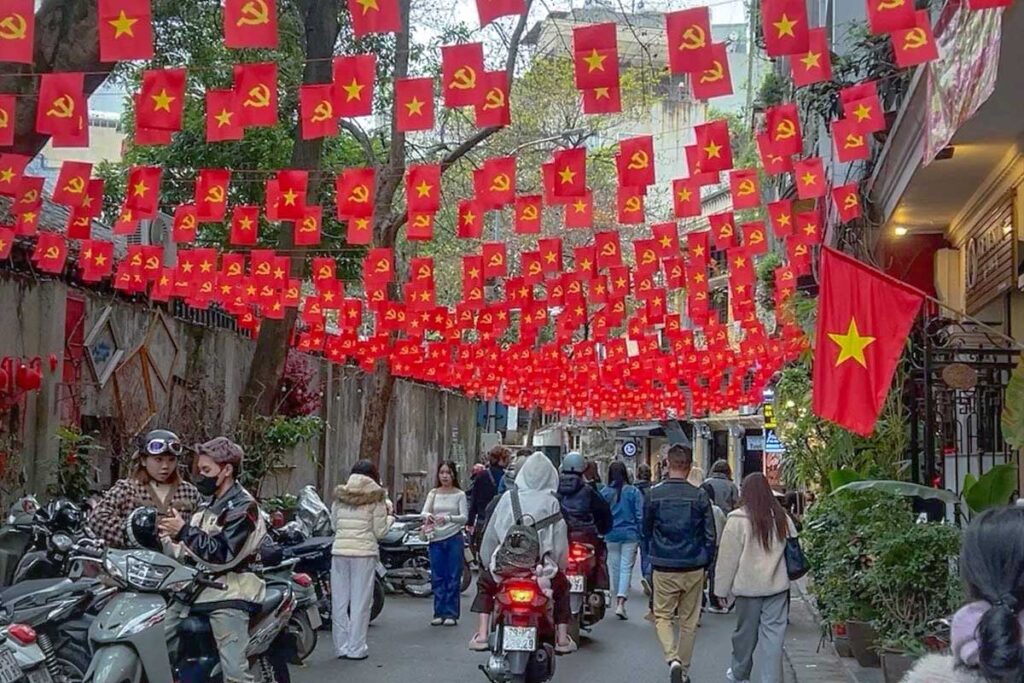 Many Vietnamese flags hanging over a small street during Reunification Day in Hanoi