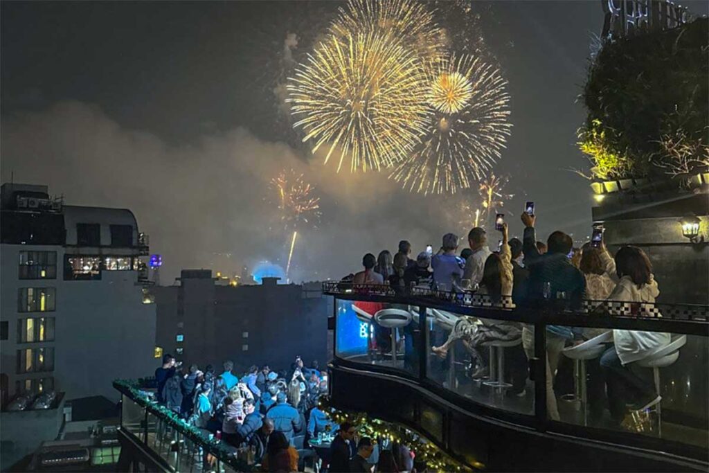 People watching the fireworks on a rooftop bar in the Old Quarter during New Year in Hanoi