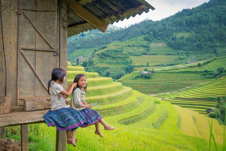 Children from ethnic minority communities sitting beside terraced rice fields in Sapa, northern Vietnam