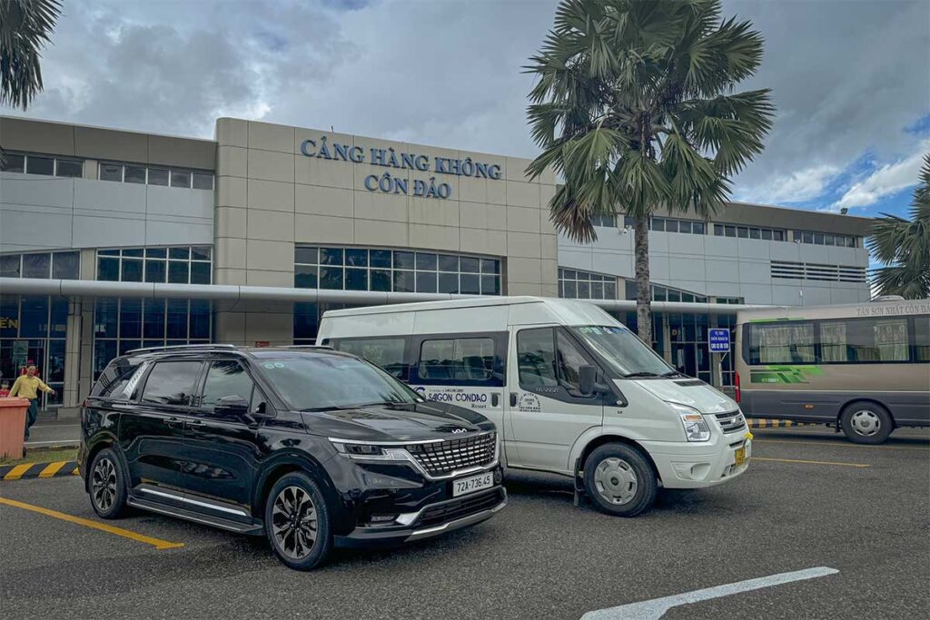 Cars and hotel shuttle vans waiting outside Con Dao Airport terminal for passenger pickup and transfers to nearby hotels